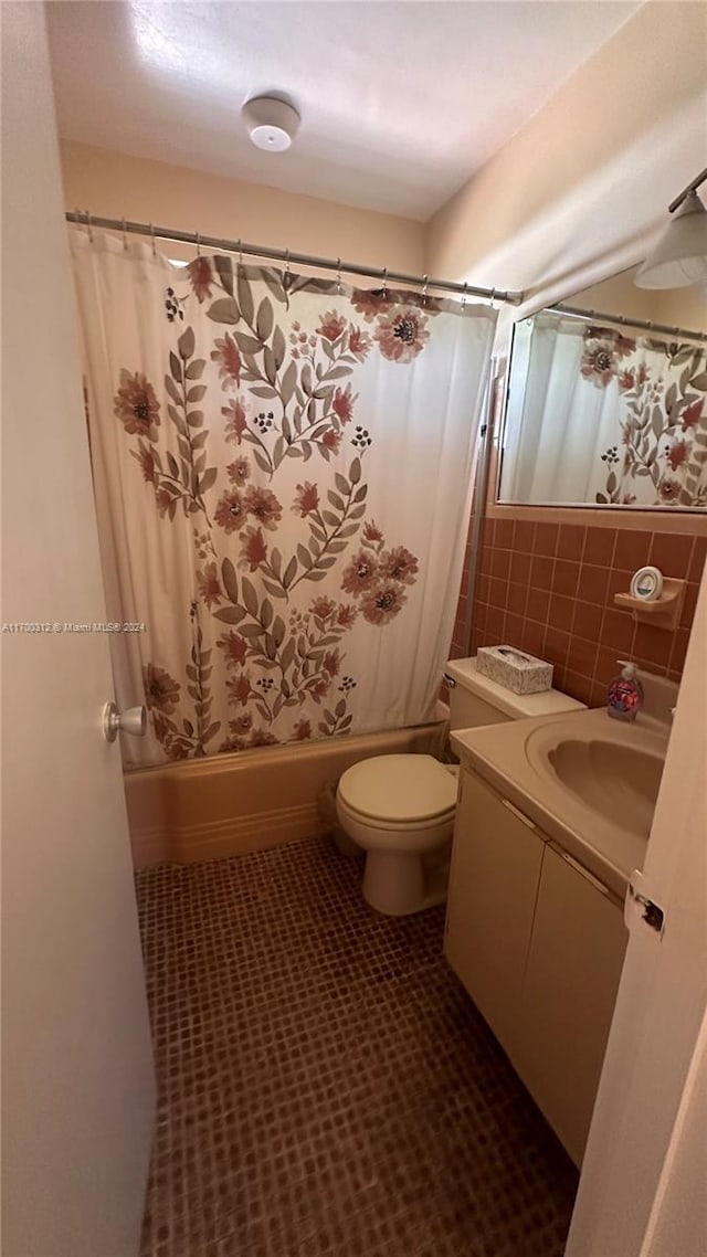 full bathroom with vanity, shower / bath combo with shower curtain, tile walls, tile patterned flooring, and toilet