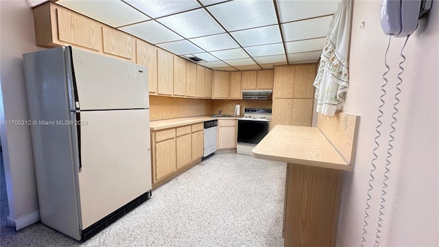 kitchen featuring a drop ceiling, range hood, white appliances, and light brown cabinetry