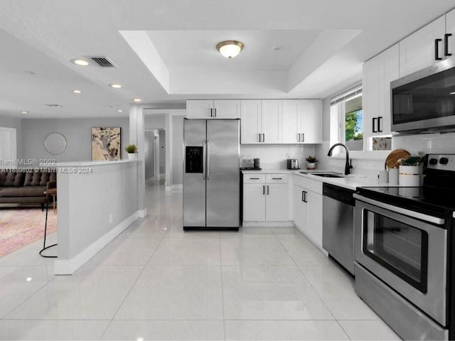 kitchen with white cabinets, a raised ceiling, sink, and appliances with stainless steel finishes