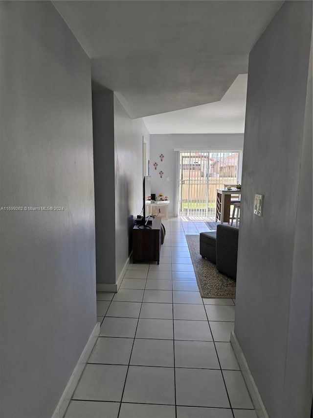 hall with light tile patterned flooring and lofted ceiling