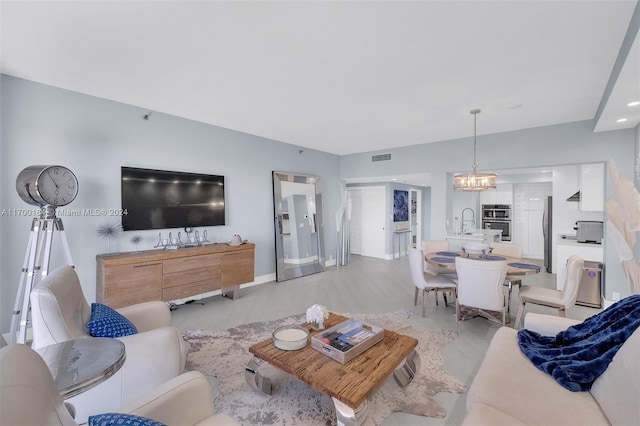 living room with a notable chandelier, light hardwood / wood-style floors, and sink