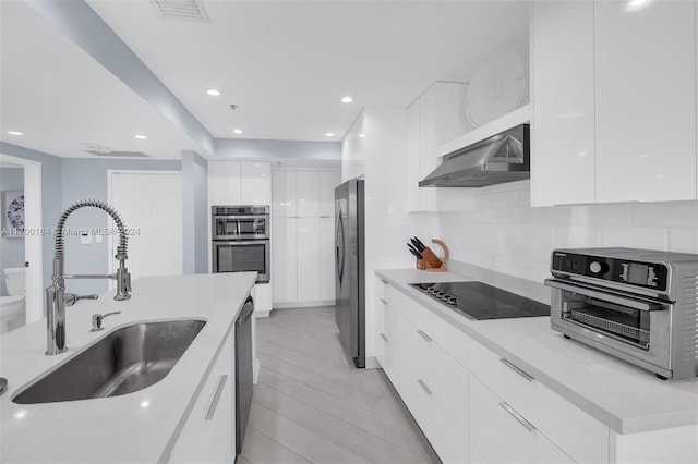 kitchen featuring white cabinetry, sink, wall chimney exhaust hood, decorative backsplash, and black appliances