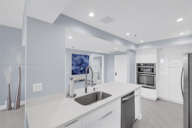 kitchen with light hardwood / wood-style flooring, stainless steel appliances, white cabinetry, and sink