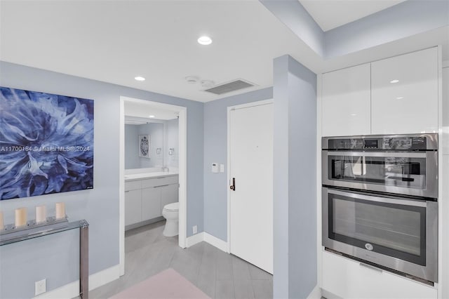 kitchen featuring white cabinets, light wood-type flooring, and double oven