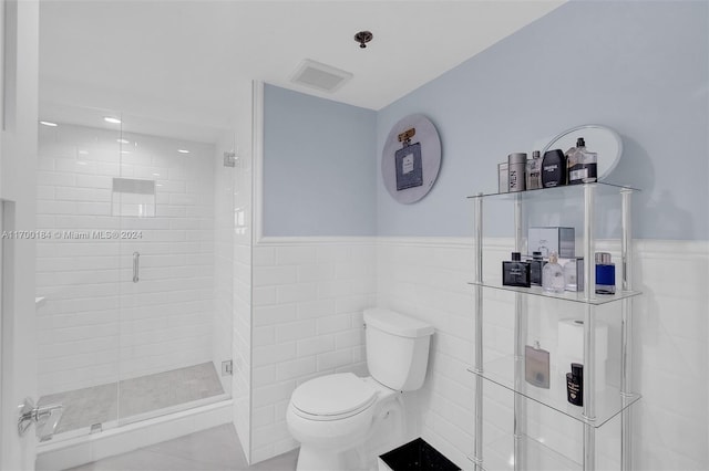 bathroom featuring tile patterned flooring, a shower with shower door, tile walls, and toilet