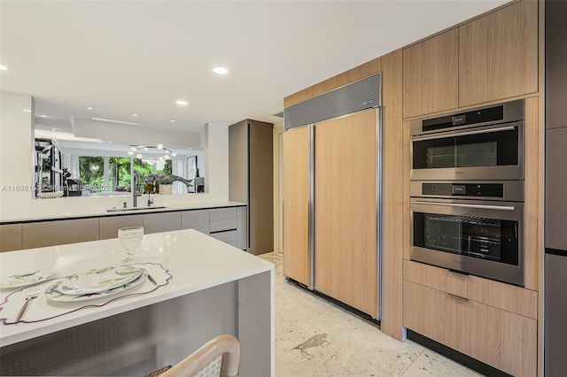 kitchen with paneled built in refrigerator, double oven, and sink