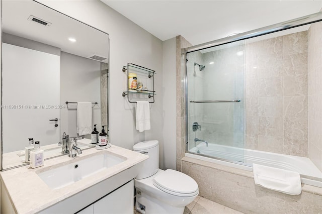 full bathroom featuring shower / bath combination with glass door, tile patterned floors, vanity, and toilet