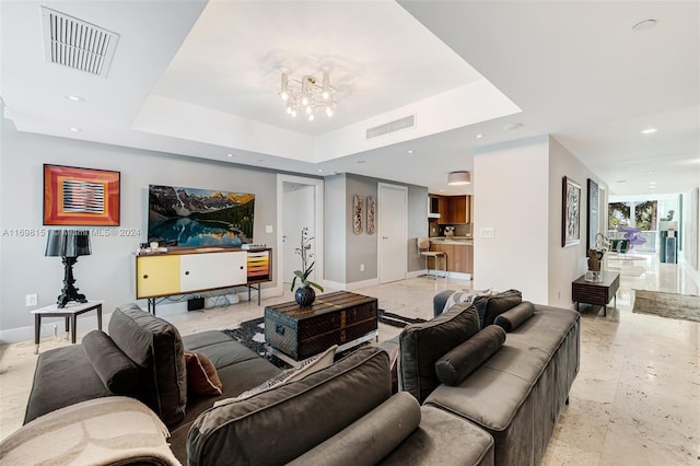 living room with a raised ceiling and a notable chandelier