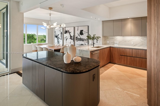 kitchen with sink, hanging light fixtures, an inviting chandelier, dark stone counters, and decorative backsplash