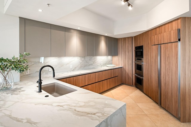 kitchen featuring sink, light stone counters, double oven, decorative backsplash, and light tile patterned floors