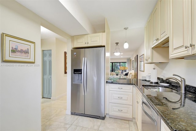 kitchen featuring decorative light fixtures, stainless steel appliances, dark stone countertops, and cream cabinetry