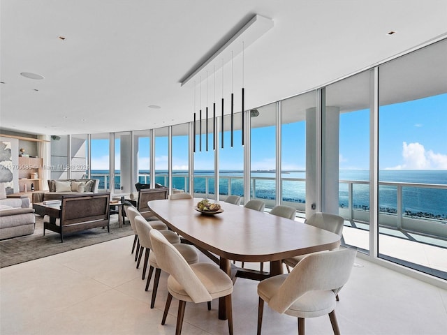 dining space with light tile patterned floors, a wall of windows, and a water view