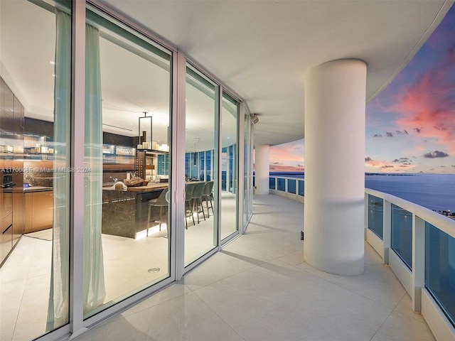 balcony at dusk featuring a water view