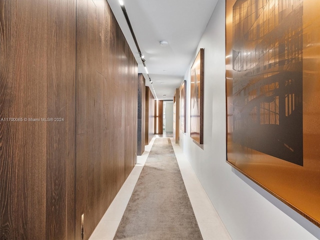 hallway featuring light tile patterned floors, wood walls, and a barn door