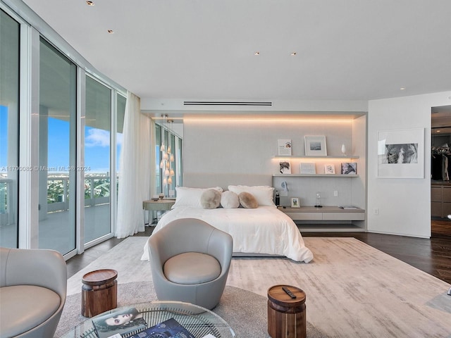 bedroom with floor to ceiling windows, access to exterior, and hardwood / wood-style flooring