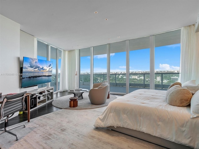 bedroom featuring wood finished floors, multiple windows, and a wall of windows