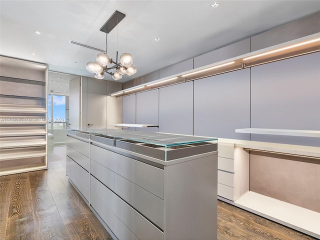 walk in closet featuring dark hardwood / wood-style floors and a notable chandelier