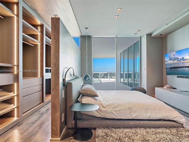 bedroom with wood-type flooring and a wall of windows