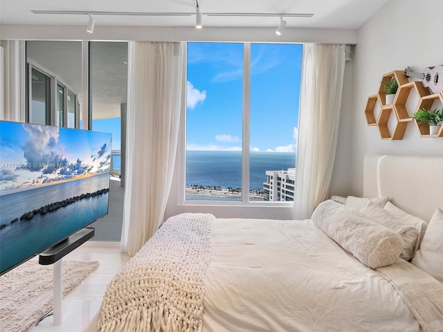 bedroom featuring light tile patterned floors, track lighting, and a water view