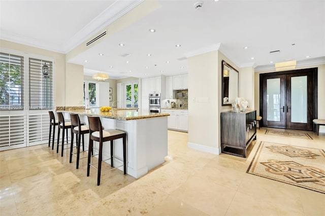 kitchen featuring a healthy amount of sunlight, white cabinetry, and crown molding