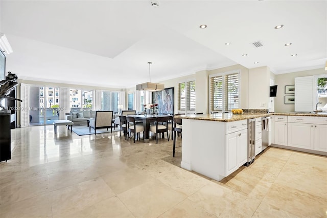 kitchen featuring white cabinetry, a wealth of natural light, light stone countertops, and decorative light fixtures