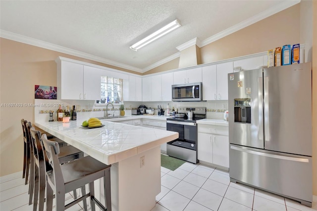 699 NW 134th Pl, Miami, FL 33182 - kitchen with a peninsula, vaulted ceiling, appliances with stainless steel finishes, decorative backsplash, and a kitchen bar