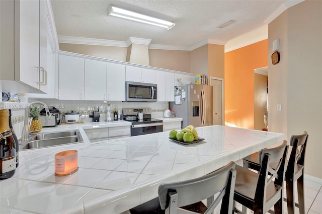 699 NW 134th Pl, Miami, FL 33182 - kitchen with ornamental molding, a peninsula, appliances with stainless steel finishes, and tile counters