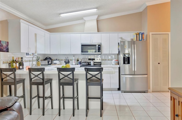 kitchen with white cabinetry, stainless steel appliances, a textured ceiling, lofted ceiling, and a breakfast bar area