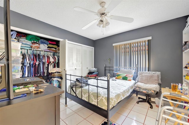 bedroom with ceiling fan, light tile patterned floors, a textured ceiling, and a closet