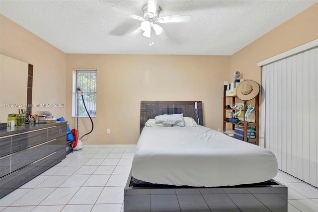 bedroom featuring ceiling fan, light tile patterned floors, and a textured ceiling