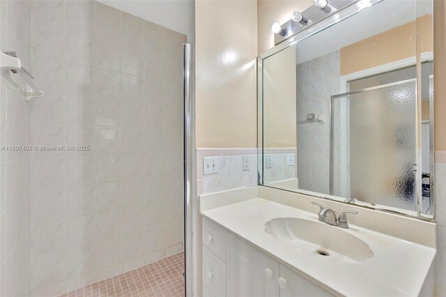 bathroom with tile walls, tile patterned flooring, vanity, and an enclosed shower