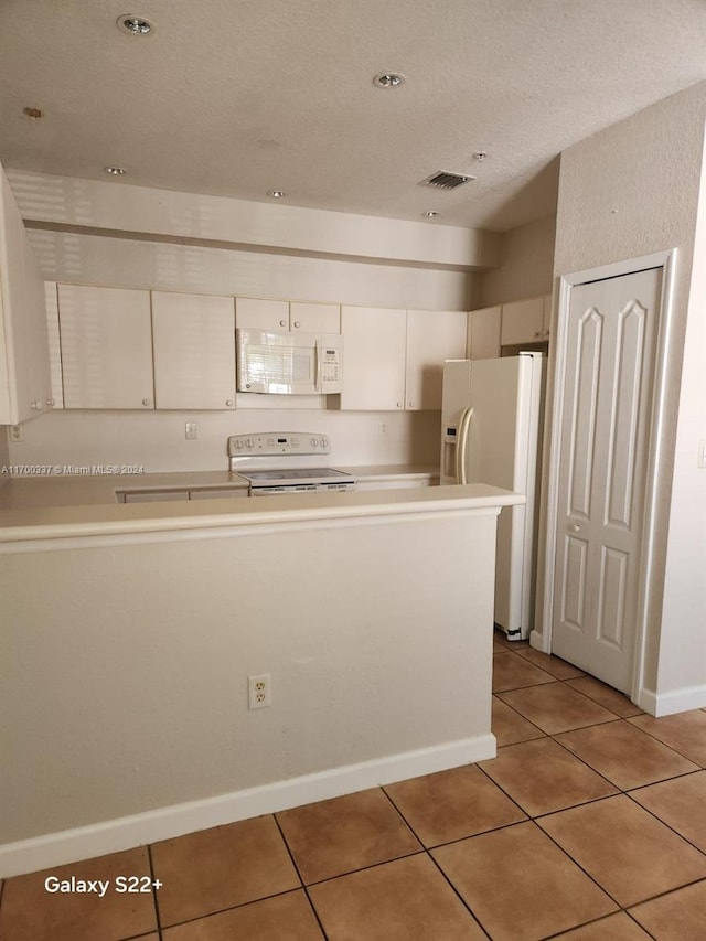 kitchen featuring white cabinets, light tile patterned floors, white appliances, and a textured ceiling