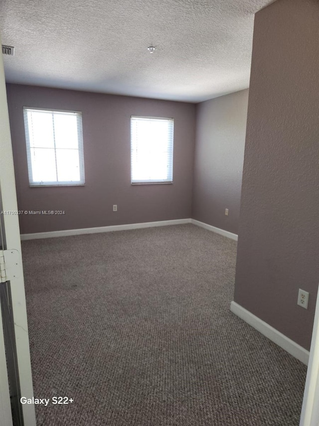 carpeted empty room with a textured ceiling