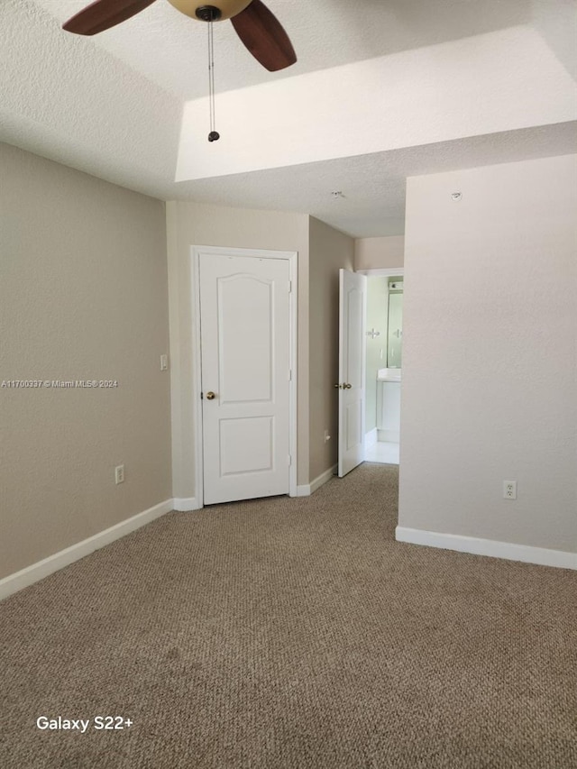 unfurnished room with a textured ceiling, carpet floors, and ceiling fan