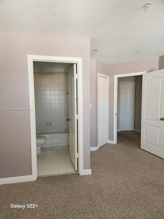 unfurnished bedroom featuring carpet, a textured ceiling, connected bathroom, and a closet