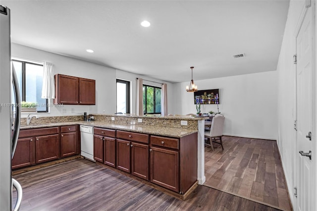 kitchen with kitchen peninsula, light stone counters, dark hardwood / wood-style floors, stainless steel refrigerator, and hanging light fixtures