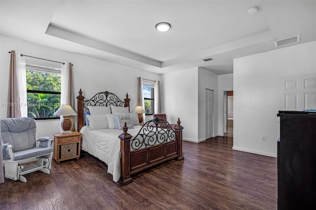 bedroom with dark hardwood / wood-style flooring and a tray ceiling