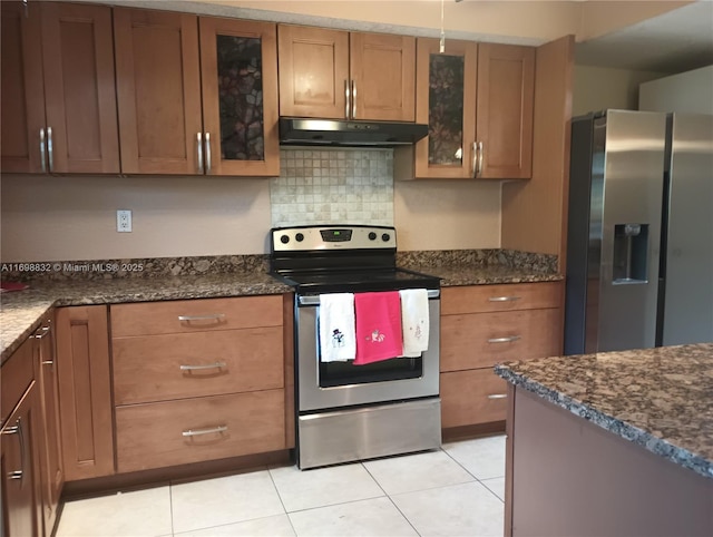 kitchen featuring light tile patterned floors, tasteful backsplash, stainless steel appliances, and dark stone countertops