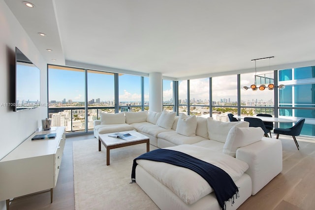 living room featuring light wood-type flooring, floor to ceiling windows, and a notable chandelier