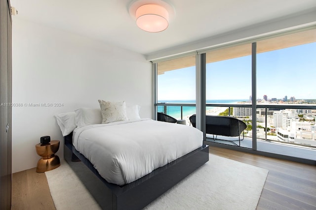 bedroom featuring access to exterior, a water view, and wood-type flooring