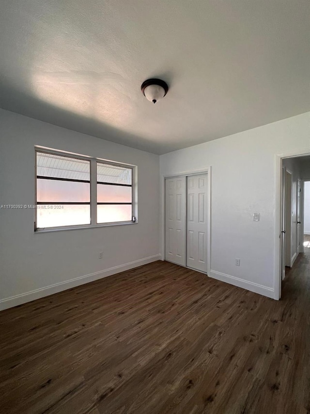 unfurnished bedroom with a closet and dark hardwood / wood-style floors