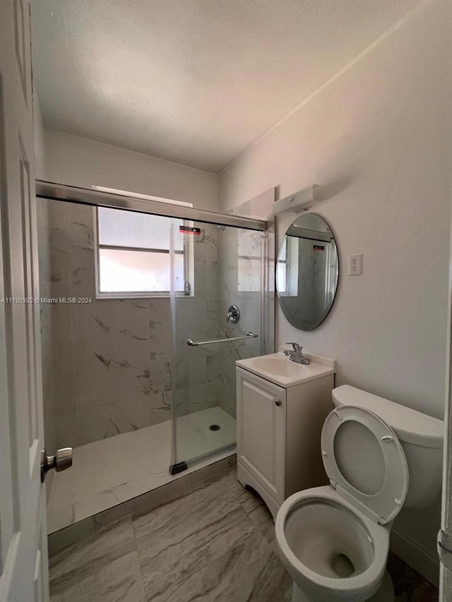 bathroom featuring vanity, toilet, and a shower with door