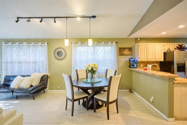 tiled dining space with sink, rail lighting, and a textured ceiling