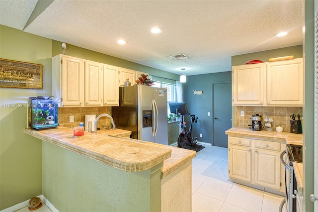 kitchen featuring backsplash, light tile patterned floors, a textured ceiling, appliances with stainless steel finishes, and kitchen peninsula