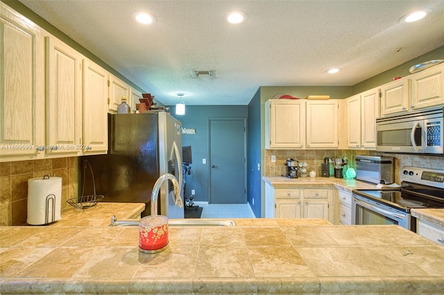 kitchen featuring tile countertops, stainless steel appliances, tasteful backsplash, and sink