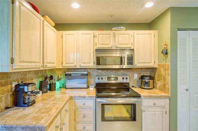 kitchen with backsplash, a textured ceiling, and appliances with stainless steel finishes