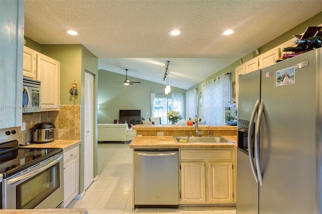 kitchen featuring appliances with stainless steel finishes, vaulted ceiling, ceiling fan, sink, and light tile patterned flooring