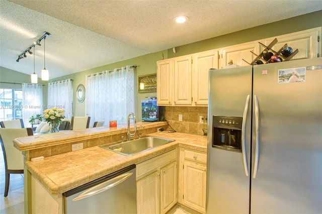 kitchen with kitchen peninsula, pendant lighting, stainless steel appliances, and sink