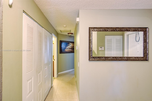 corridor featuring light tile patterned floors and a textured ceiling