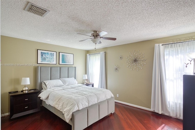 bedroom featuring a textured ceiling, dark hardwood / wood-style floors, multiple windows, and ceiling fan